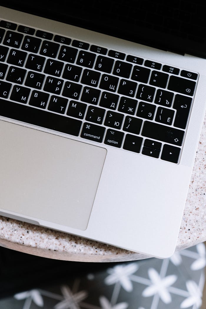 Overhead shot of a modern laptop with Cyrillic keyboard on a textured surface.